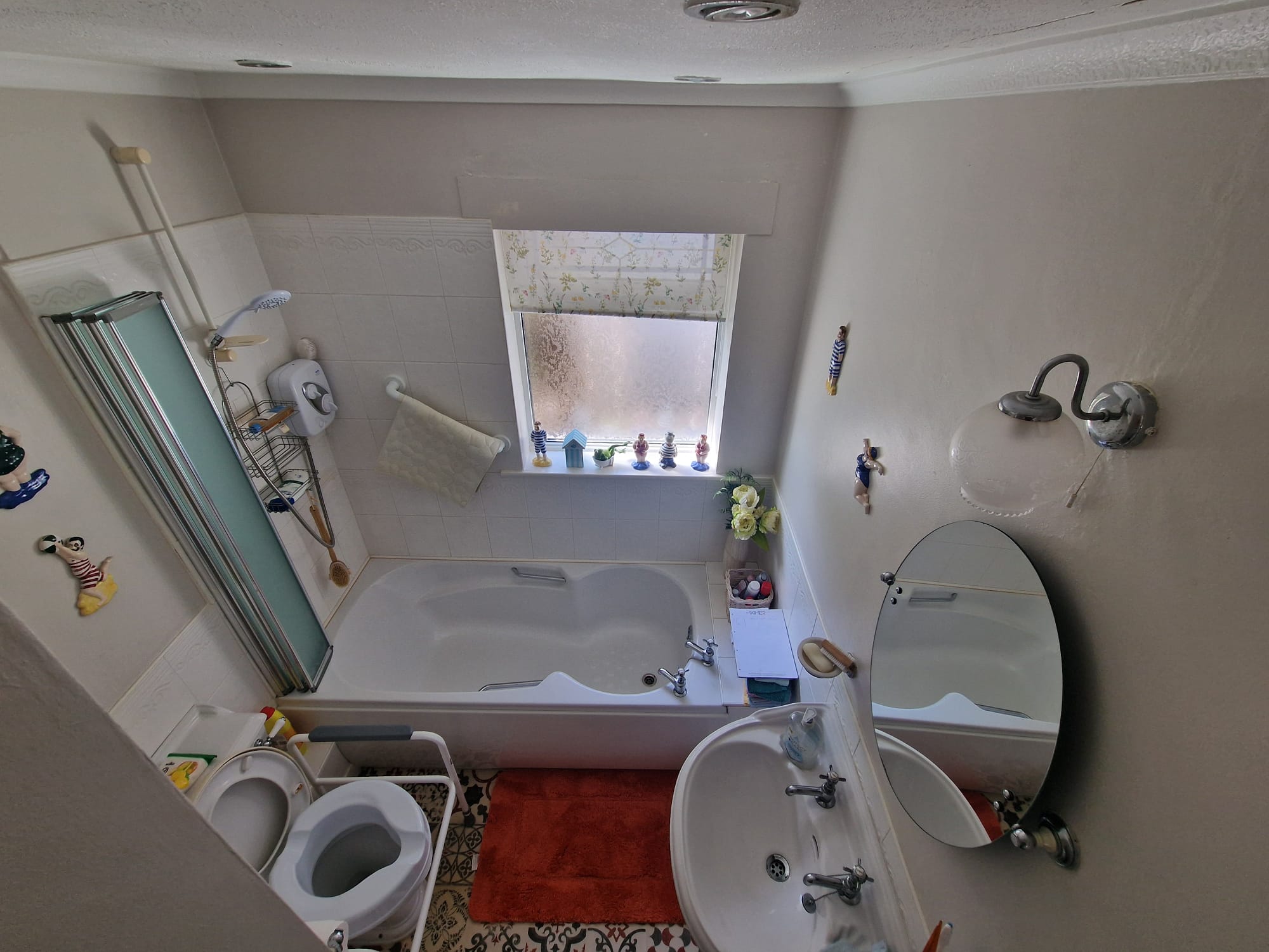 Original bathroom with a bath, shower screen and toilet support frame before conversion